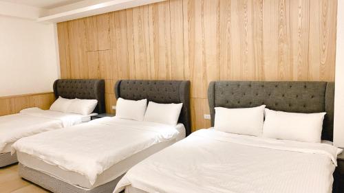 Duas camas num quarto com lençóis e almofadas brancos em Enjoy staying em Magong