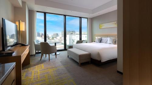 a hotel room with a bed and a large window at Miyako Hotel Hakata in Fukuoka
