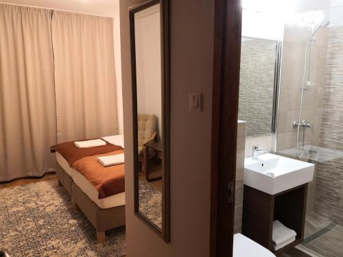 a bathroom with a bed and a sink and a mirror at Laguna Panzió in Gárdony