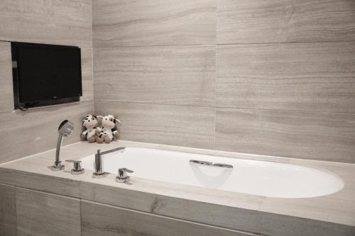 a bathroom with a white tub and a tv at Jinling Grand Hotel in Hefei
