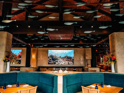 a dining room with tables and a large screen at Miyakojima Tokyu Hotel & Resorts in Miyako-jima