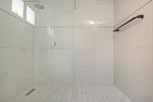 a white bathroom with a shower with a glass door at Sea De La Vie 25 by Host Agents in La Mercy
