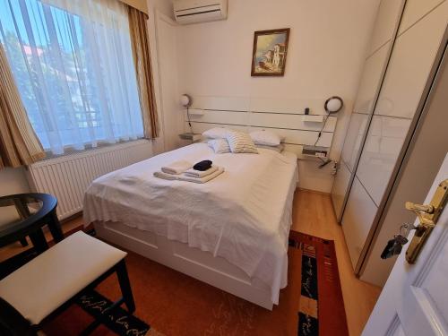 a bedroom with a bed with white sheets and a window at Abigél Vendégház in Miskolctapolca