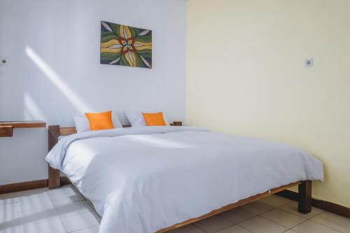 a bedroom with a white bed with orange pillows at Nafisa Homestay Syariah Near Jatim Park 3 Batu Mitra RedDoorz in Malang