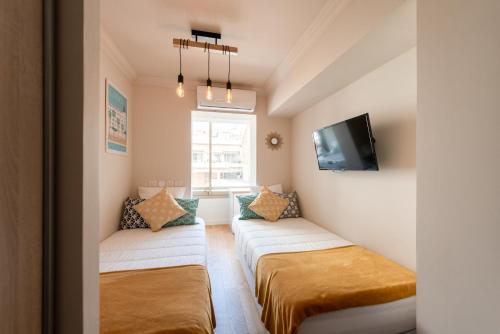 une petite chambre avec deux lits et une télévision dans l'établissement Magnifique 3 pièces en plein cœur de Cannes, à Cannes