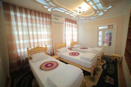 Habitación con 3 camas y lámpara de araña. en Old Street Guesthouse, en Bukhara