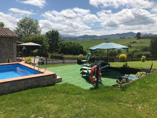 a backyard with a swimming pool and an umbrella at EL HOGARIN DE ARRIONDAS in Arriondas