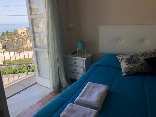 una camera con un letto blu e una grande finestra di Lo Splendore del Borgo a Tropea