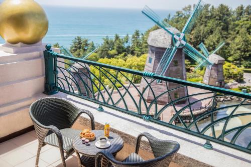 a table and chairs on a balcony with a windmill at Lotte Hotel Jeju in Seogwipo