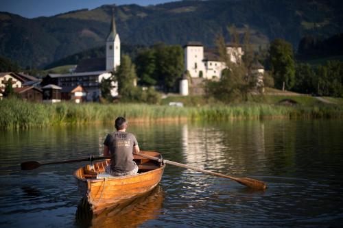 a man is rowing a boat in the water at Bio-Bauernhof Reitmayrgut in Goldegg