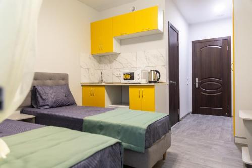 a room with two beds and a kitchen with yellow cabinets at Zenith Hotel in Odesa