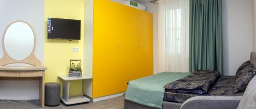 1 dormitorio con puerta amarilla, cama y espejo en Zenith Hotel, en Odessa