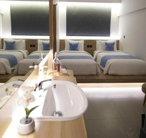 een badkamer met 3 bedden, een wastafel en een spiegel bij QUBIKA BOUTIQUE HOTEL in Tangerang