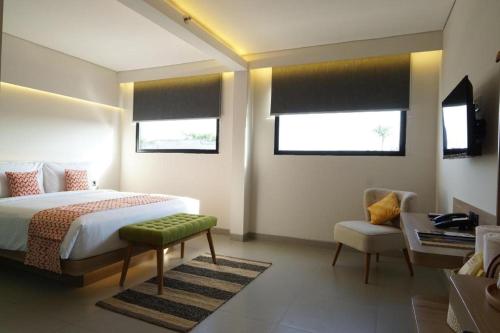 een slaapkamer met een bed en een stoel en 2 ramen bij QUBIKA BOUTIQUE HOTEL in Tangerang