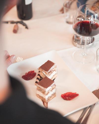 a plate with two pieces of cake and a glass of wine at Hotel La Soldanella in Moena