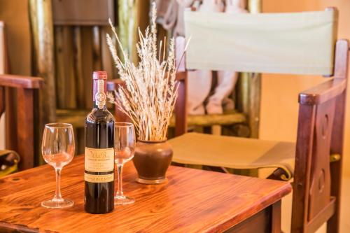 a bottle of wine sitting on a table with two glasses at Bagatelle Kalahari Game Ranch in Hardap