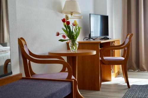 een hotelkamer met een tafel met een vaas met bloemen erop bij Pension zum Ritter in Katzhütte