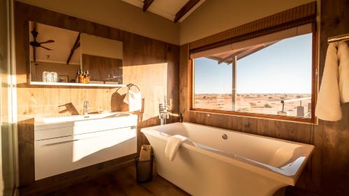 a bathroom with a tub and a sink and a window at Bagatelle Kalahari Game Ranch in Hardap