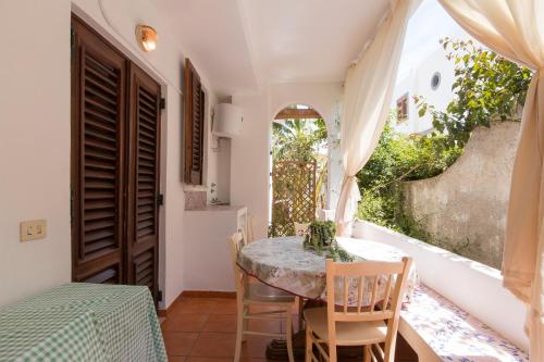 una sala da pranzo con tavolo, sedie e finestra di Il giardinetto Lipari centro a Città di Lipari