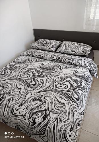 a bed with a black and white blanket and pillows at Quiet place in Beʼer Ora