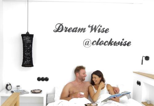 a man and a woman sitting in bed with a book at Clock Wise Syros in Ermoupoli