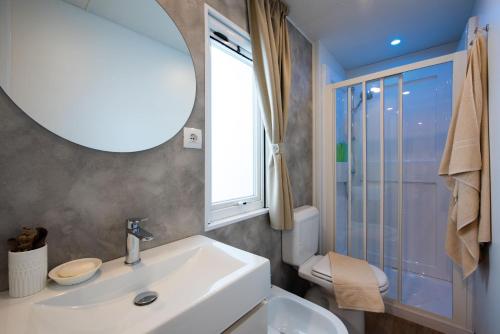 La salle de bains est pourvue d'un lavabo, d'un miroir et de toilettes. dans l'établissement Bungalow Lido, à Colico