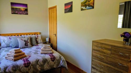 a bedroom with a bed and a wooden dresser at Uig Chalets Idrigill Hill Chalet in Uig