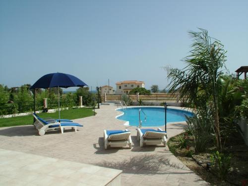a swimming pool with lounge chairs and an umbrella at Holidays Villas in Pissouri
