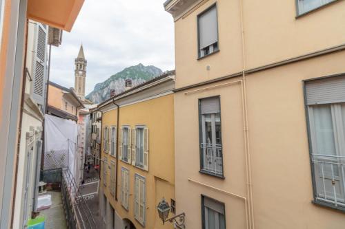 an alley with buildings and a clock tower in the distance at Le Casette Di Osvaldo in Lecco