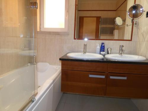 a bathroom with two sinks and a tub and a shower at Apartamento Phillipe in Odiáxere
