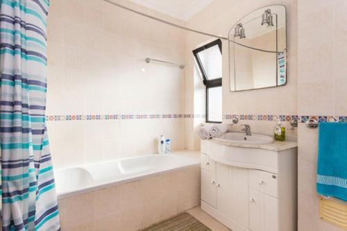 ein Badezimmer mit einer Badewanne, einem Waschbecken und einem Spiegel in der Unterkunft calm beach apartement in Portimão