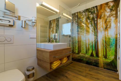 a bathroom with a sink and a forest mural on the wall at Hotel Rosenstein in Heubach