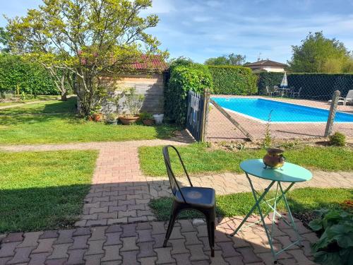 - une table et une chaise à côté de la piscine dans l'établissement La maison du Bonheur, borne de recharge VE, à Saint-Bernard