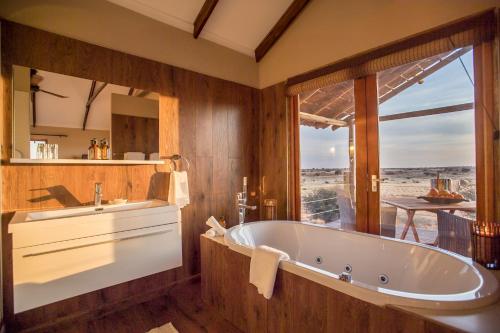 uma casa de banho com uma banheira grande e uma janela grande em Bagatelle Kalahari Game Ranch em Hardap