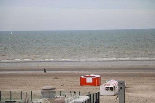 a red shack on a beach with the ocean at Noble dune in Oostduinkerke
