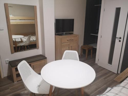 a white table and chairs in a room with a television at Penzion-Cukroška in Hlušovice