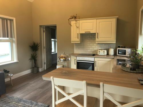 a kitchen with white cabinets and a wooden table at The Lodge - Rural Tipperary bordering Kilkenny 