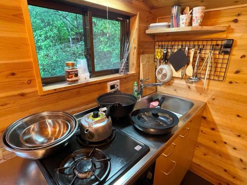 a kitchen with a stove and a sink in a log cabin at るり渓 フレアキャビン in Nantan city