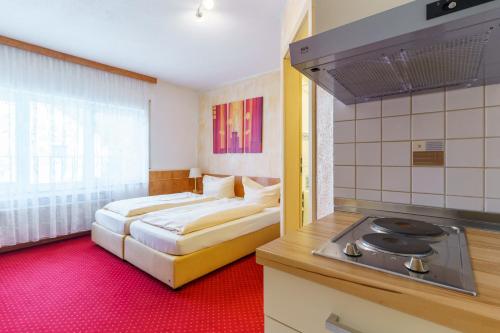 a bedroom with a bed and a kitchen with a stove at Hotel Rosenstein in Heubach