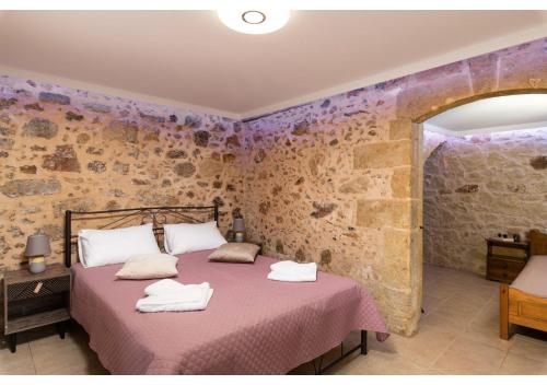 a bedroom with a bed and a stone wall at Poseidon Apartments in Kissamos