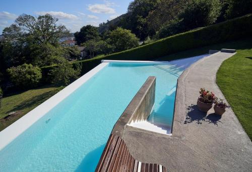 フェロルにあるApartamento con piscina y excelentes vistasの塀と鉢植えの植物2本が植えられたスイミングプール