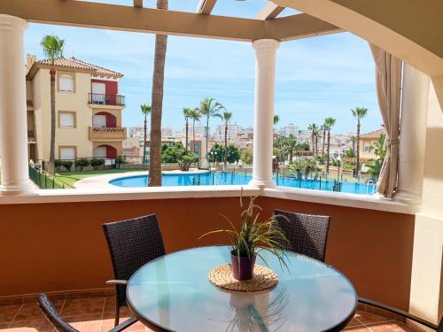 una mesa y sillas en un balcón con vistas a la piscina en Apartamento Narváez- Altos Del Tomillar, en Torre del Mar