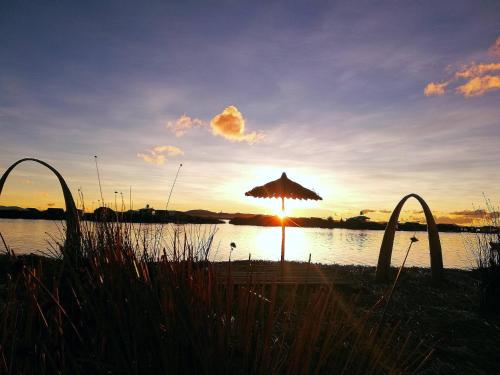 - un parasol sur la plage avec le coucher du soleil en arrière-plan dans l'établissement Room in Lodge - Lucsay Titicaca Lodge, à Puno