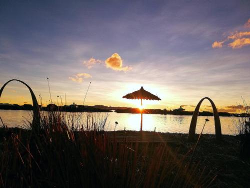 an umbrella on the beach with the sunset in the background at Lucsay Titicaca Lodge in Puno