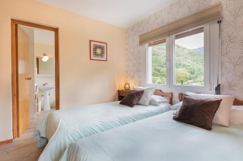 two beds in a room with a window at HostalTina in Bossost