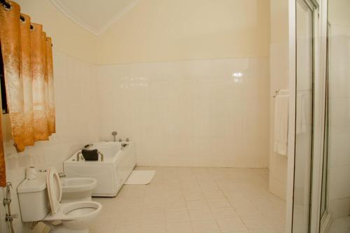 a white bathroom with a toilet and a sink at A1 Hotel and Resort in Arusha