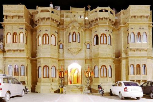 um grande edifício com carros estacionados em frente em Hotel Lal Garh Fort And Palace em Jaisalmer