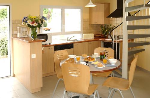 une cuisine avec une table et des chaises avec de la nourriture. dans l'établissement Village de Gîtes de l'Anse de Moidrey, à Moidrey