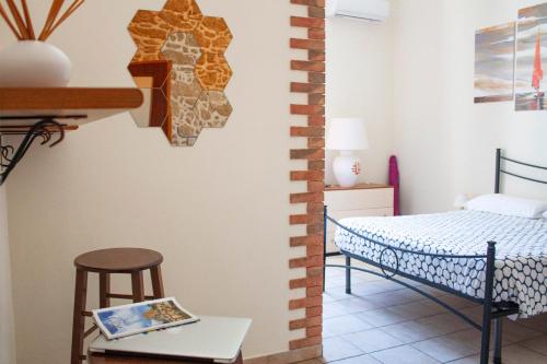 アルゲーロにあるPoseidon Algheroのベッド1台、テーブル、スツールが備わる客室です。
