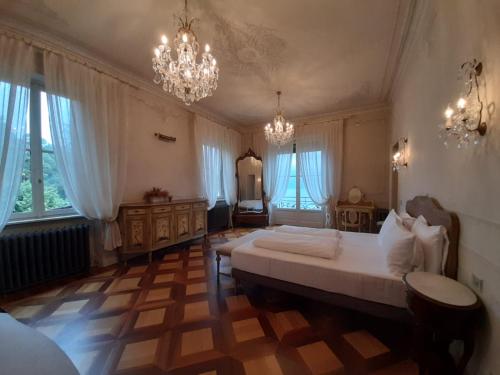 カンノビオにあるVILLA SASSO Dimora di Lagoの大きなベッドとシャンデリアが備わる広いベッドルーム1室が備わります。